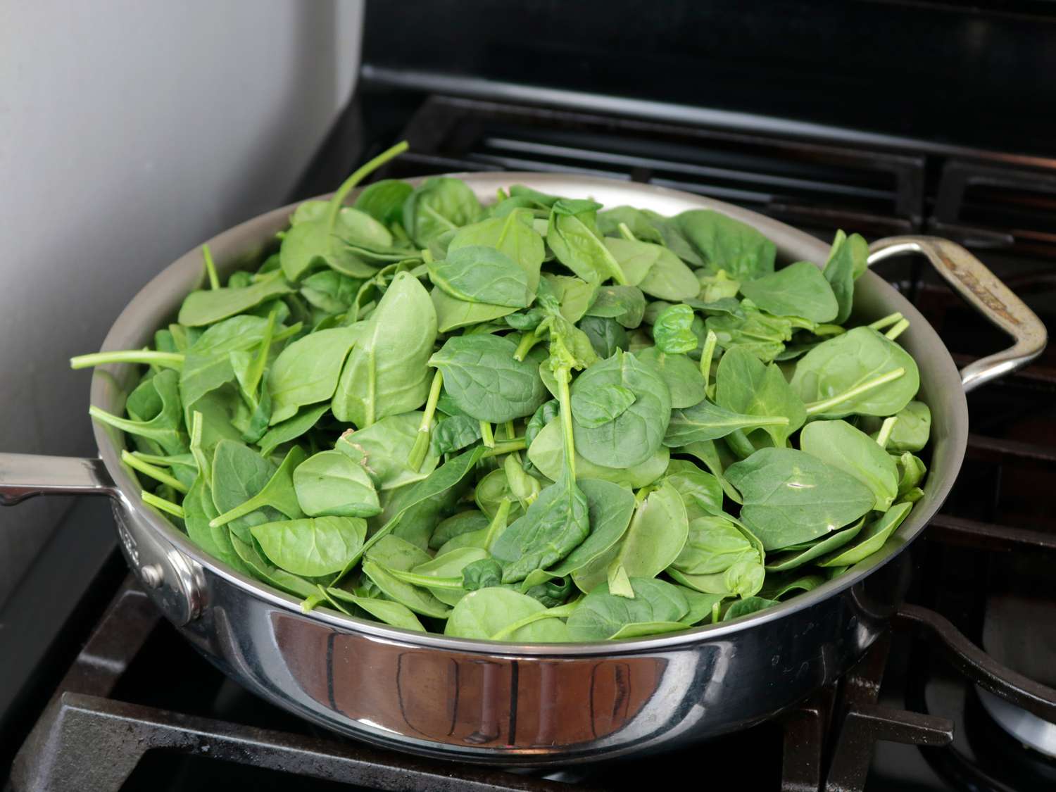 a bunch of spinach wilting in a saute pan
