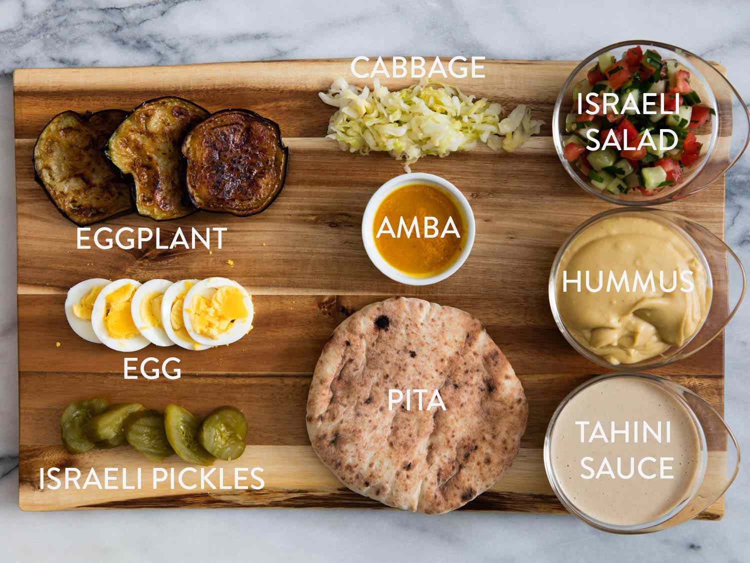 萨比希三明治的所有成分，炸茄子，卷心菜，安巴，沙拉，煮鸡蛋，以色列泡菜，皮塔饼，鹰嘴豆泥和芝麻酱。