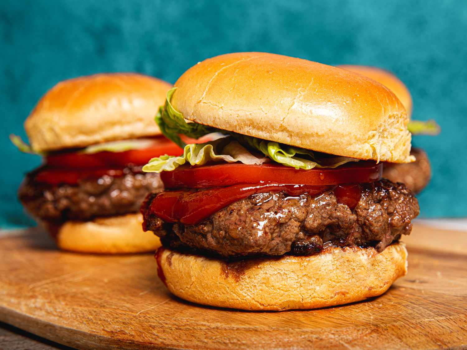 Wagyu burgers on a bun with ketchup, tomato and lettuce.