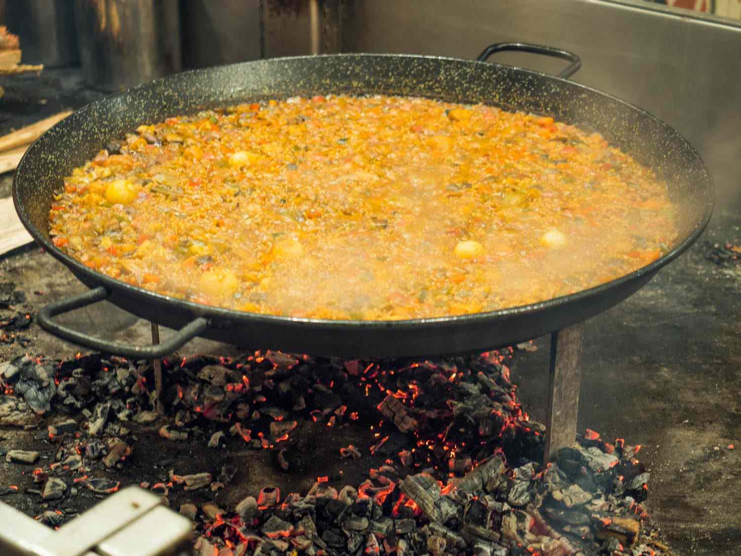 在纽约的梅尔卡多小西班牙餐厅，一大块蔬菜海鲜饭在余烬上完成。海鲜饭平底锅高高架在一个铁架上，这样厨师就很容易控制下面的火和余烬。gydF4y2Ba