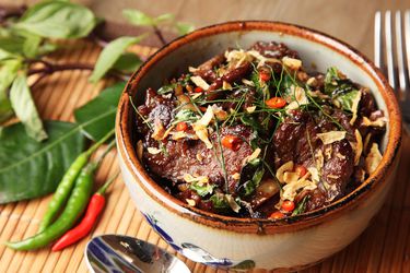 一个装满泰式牛肉、罗勒和辣椒的陶瓷碗。