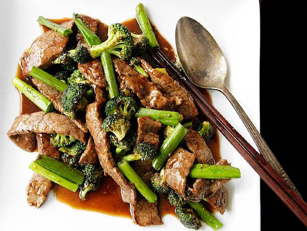 用筷子和勺子在盘子里炒牛肉和西兰花。