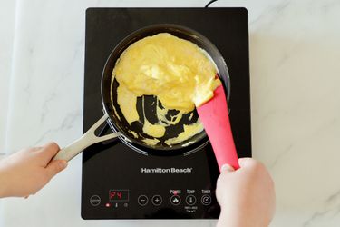 cooking scrambled eggs in a pan on an induction burner