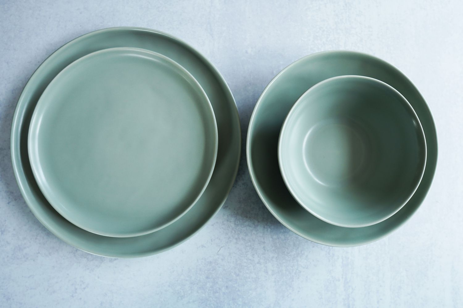 two green bowls and plates on a grey surface