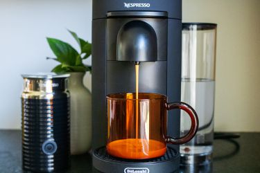 A Nespresso machine brewing a cup of coffee into an amber mug