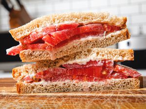 经典的番茄三明治放在砧板上，斜切并堆叠