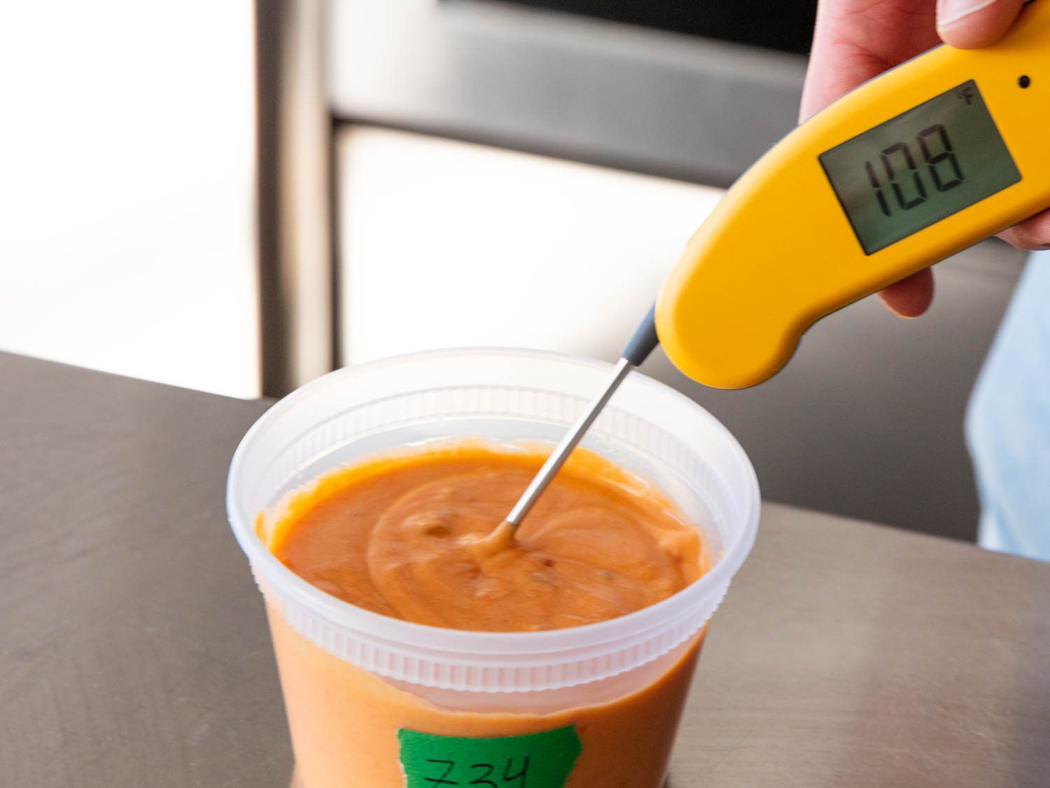 用温度计测量塑料容器里的奶酪酱的温度。