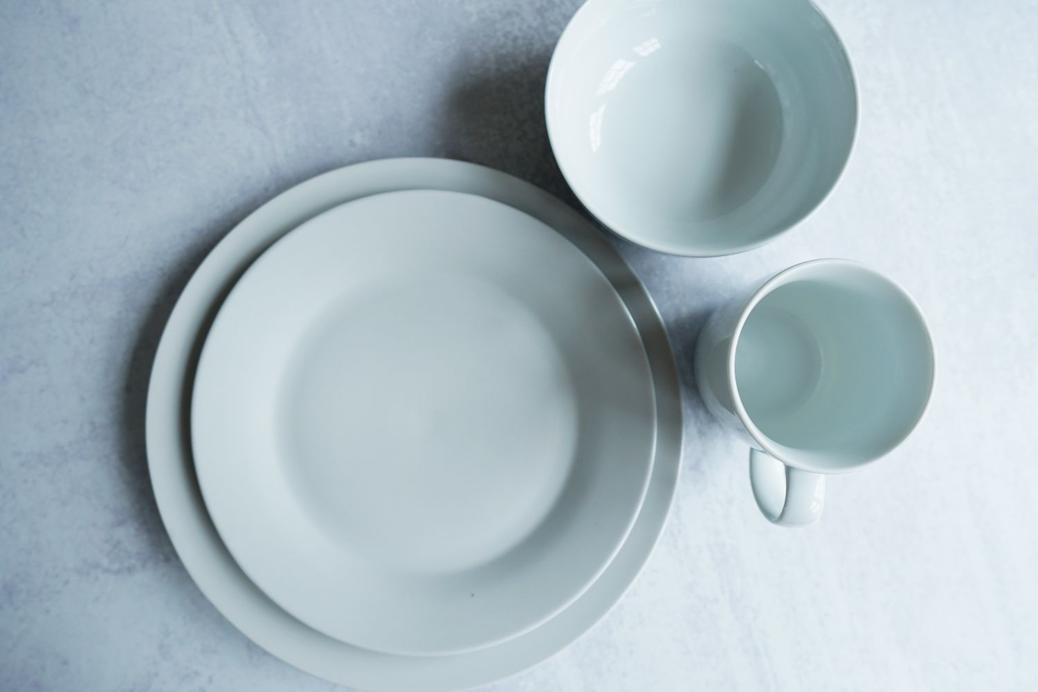 a white dinnerware set on a grey surface