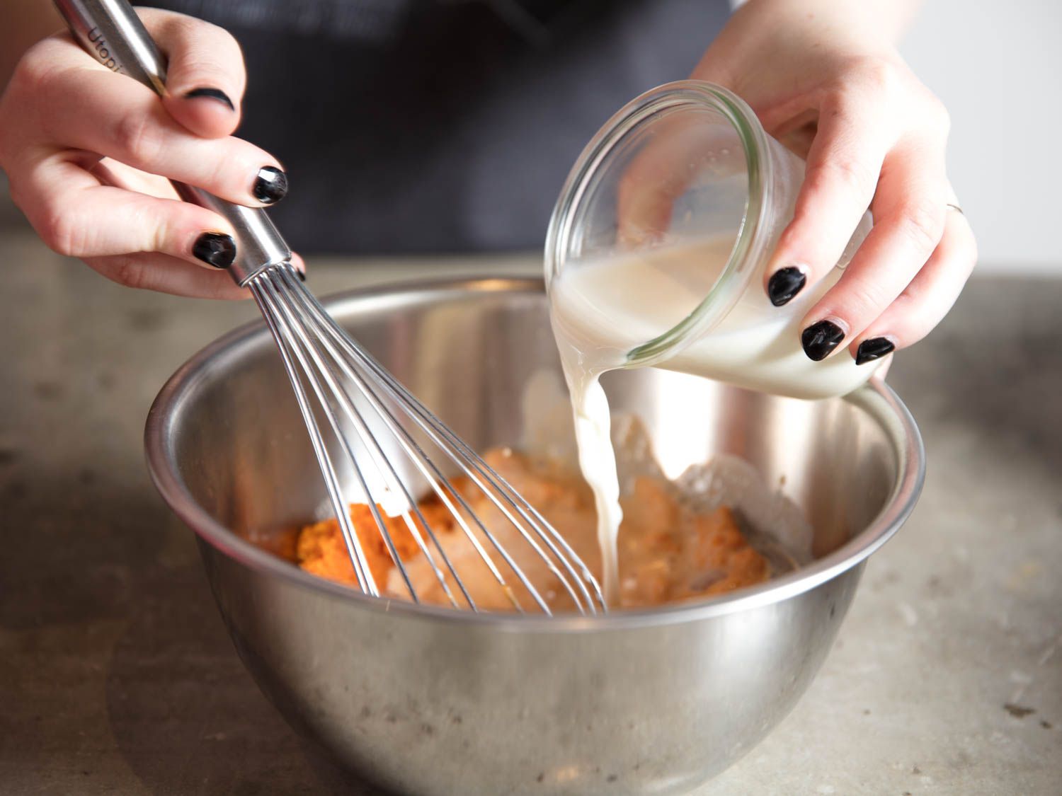 Whisking milk with pumpkin purée in a metal mixing bowl