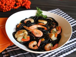 A bowl of black squid ink pasta with shrimp and scallops