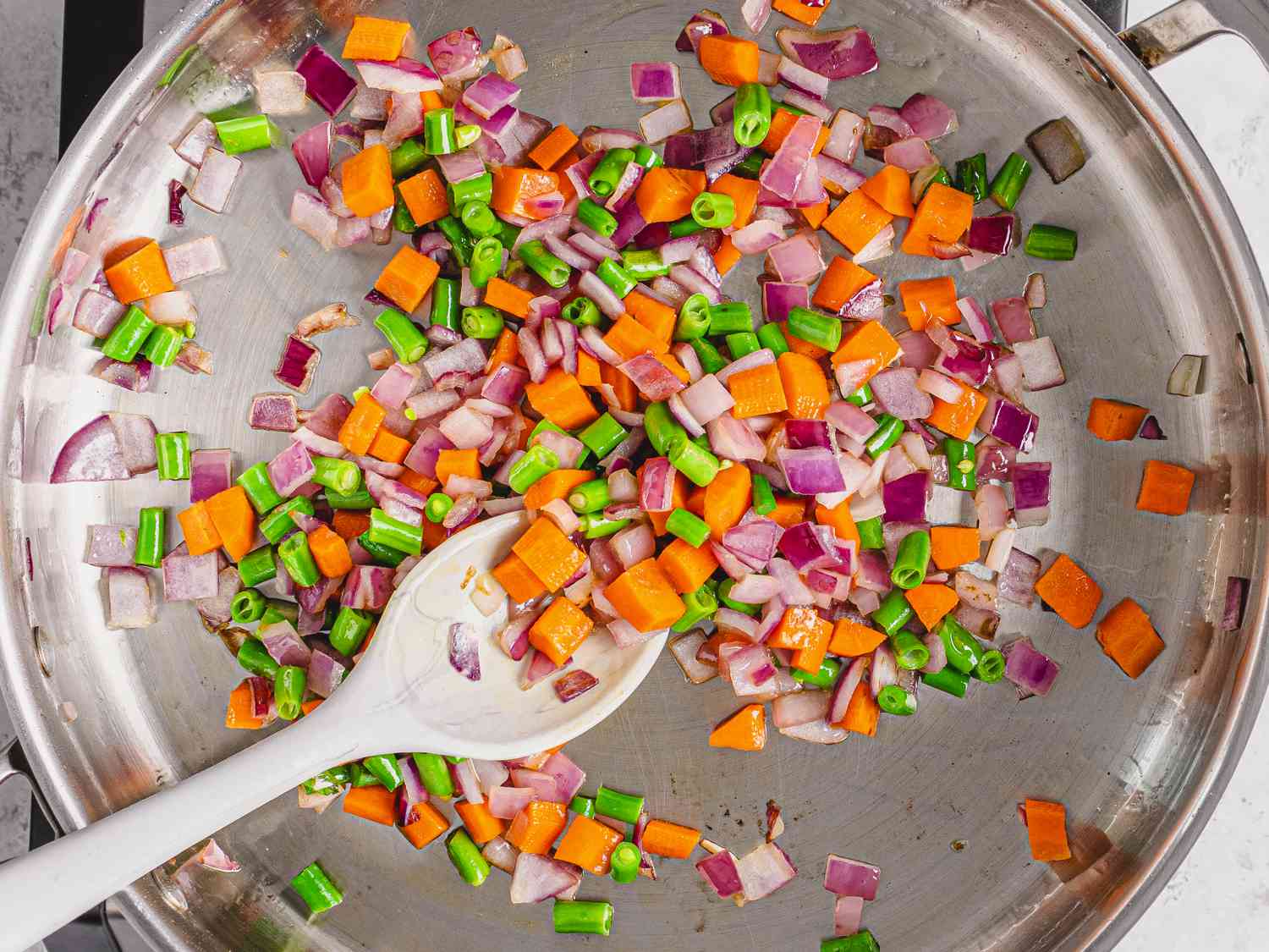 将洋葱、胡萝卜和青菜放入油煎锅