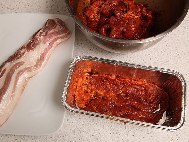 将未煮熟的腌猪肉里脊和生培根分层放入一个铝烤盘。