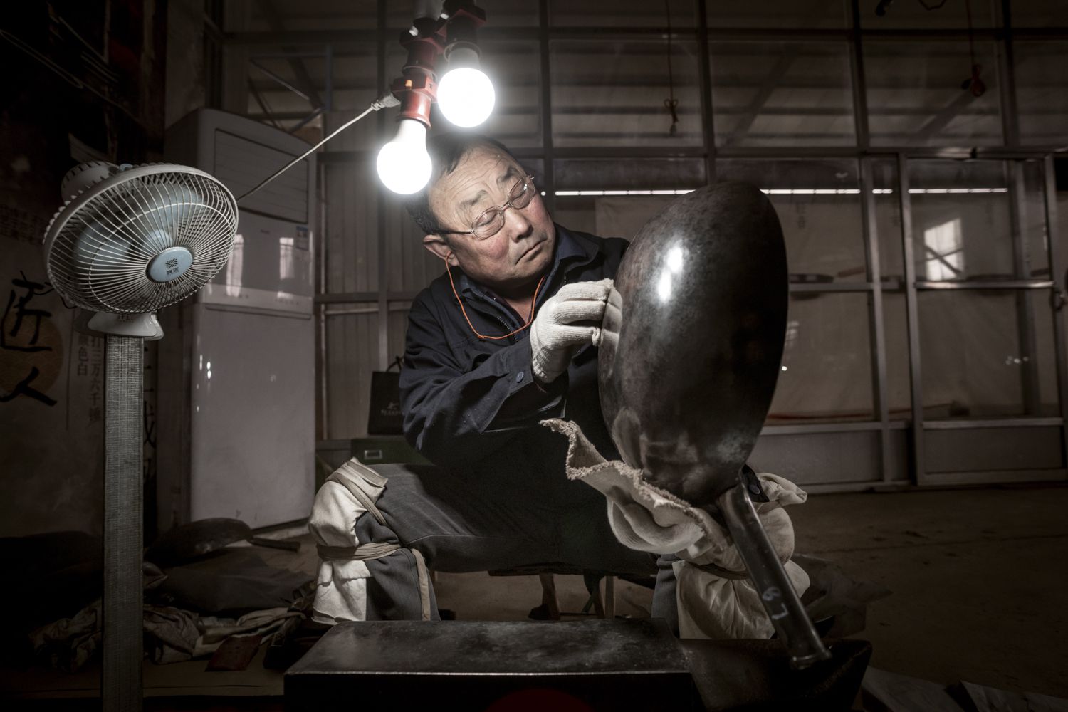 一名工厂工人在两个灯泡下擦手锤锅