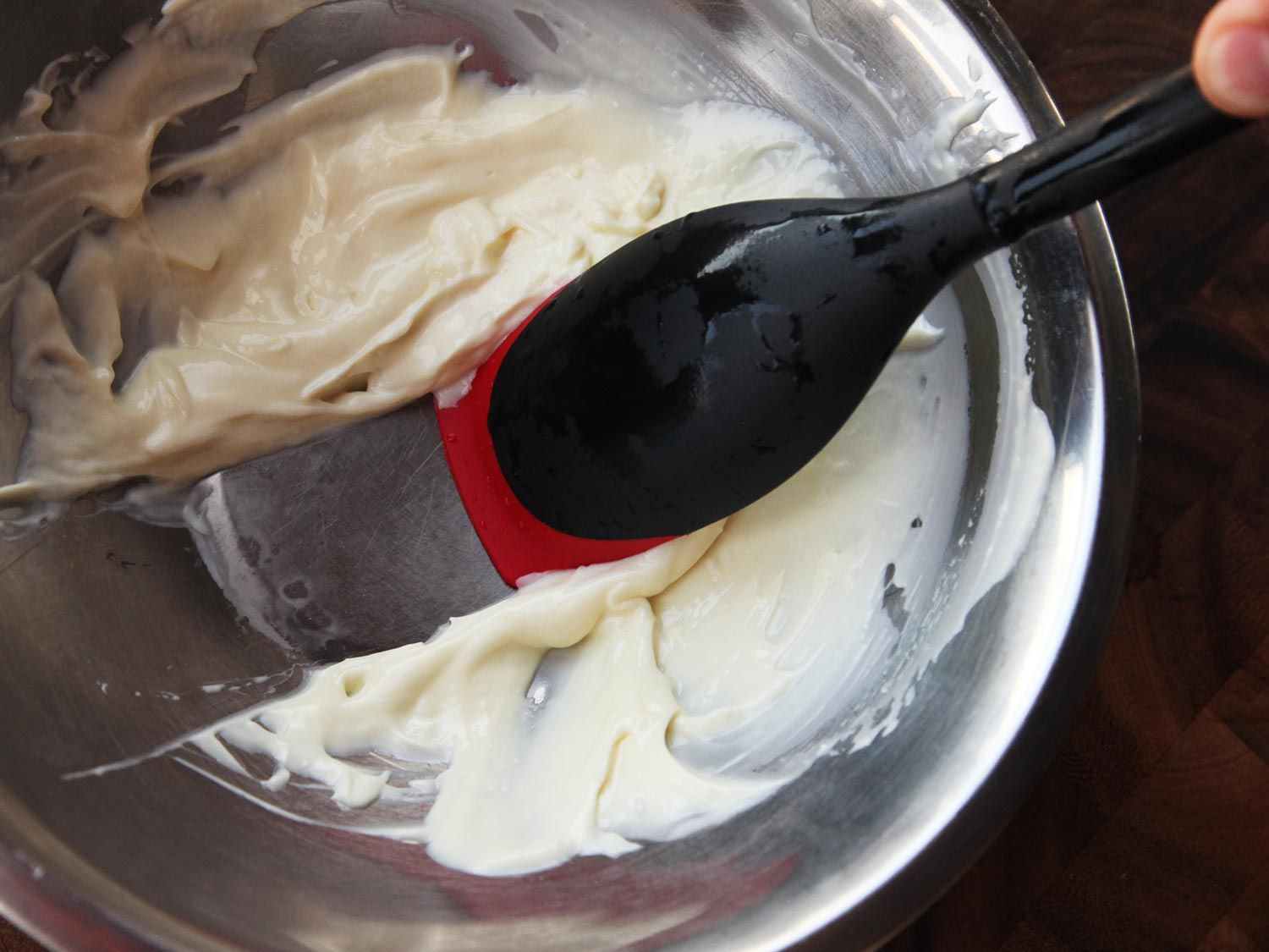 Le Creuset silicone spoon scraping Mayonnaise in a bowl