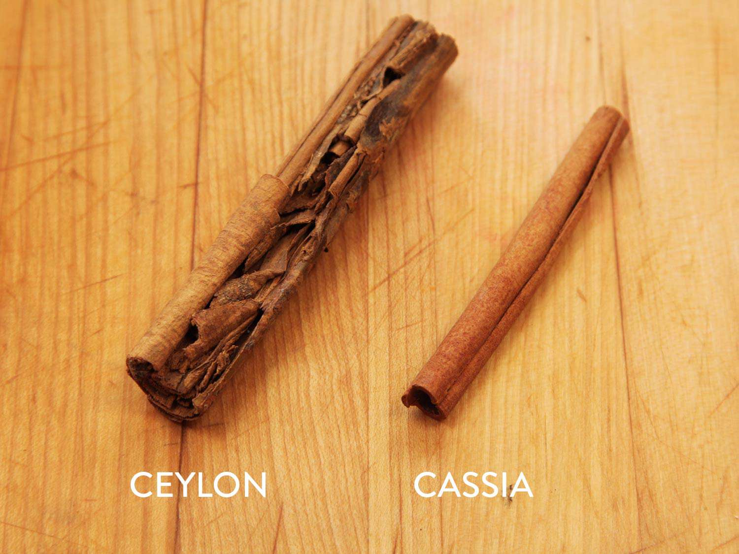 A stick of ceylon cinnamon next to a stick of cassia cinnamon. The Ceylon cinnamon is larger and a different texture.