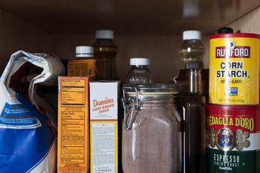 Homemade brownie mix on the pantry shelf, along with a bag of flour, box of baking soda, a box of brown sugar, a can of cornstarch, a can of espresso powder, and a few bottles.
