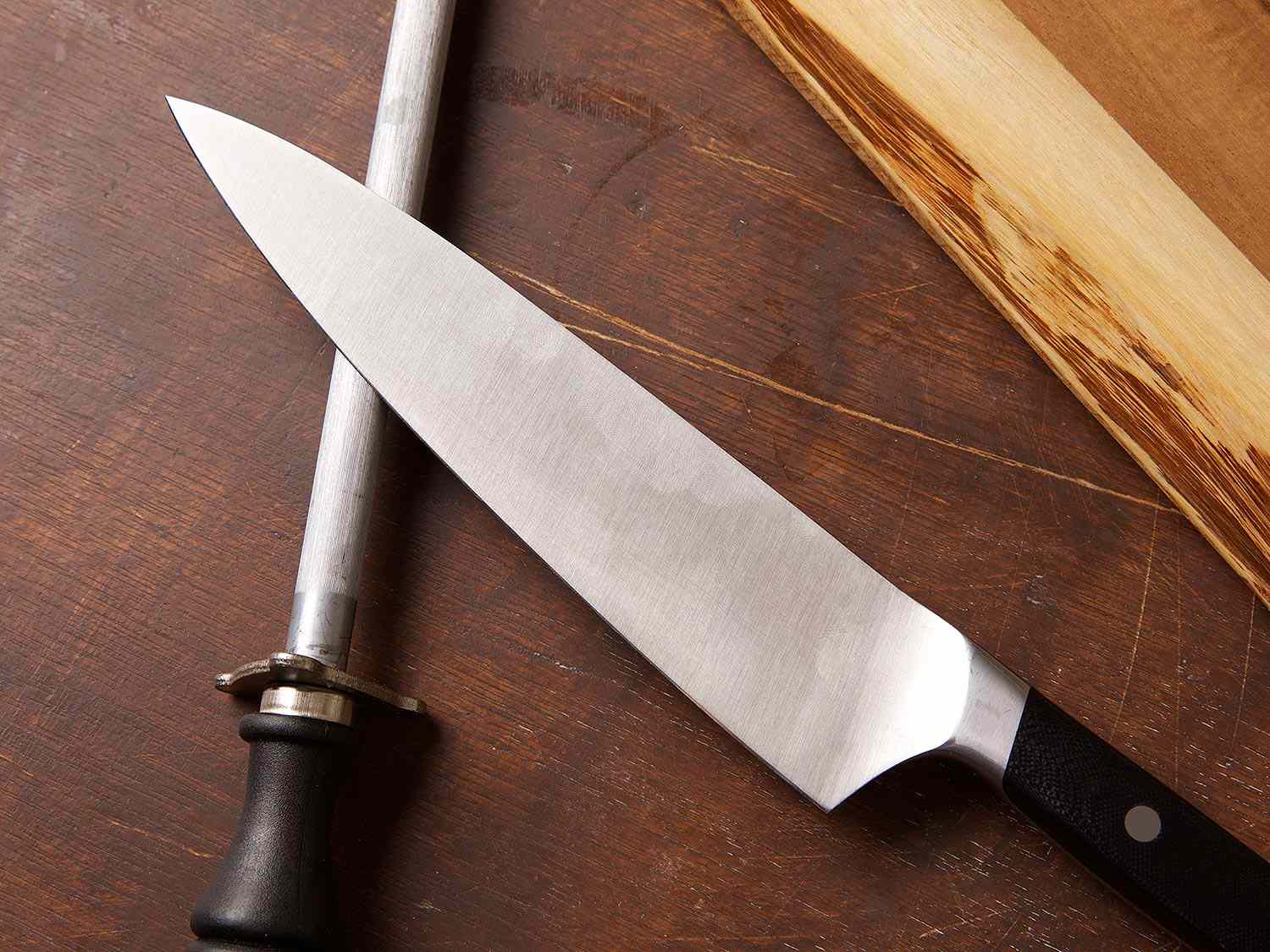 一把厨刀和一根珩磨棒放在木板上