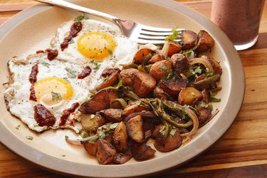 Plate with two sunny side-up eggs, a pile of home fries, and a fork