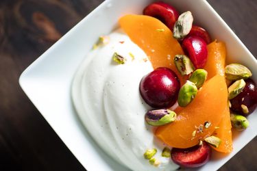头顶的镜头是一碗夏天的水果和用开心果装饰的打发的希腊酸奶