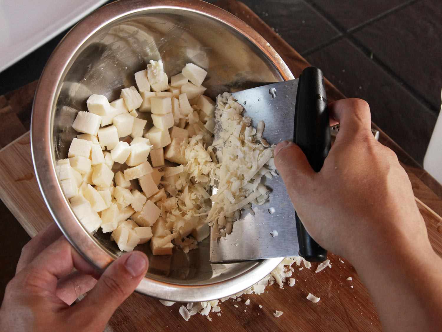Combining cubes of mozzarella with grated Parmesan in a bowl