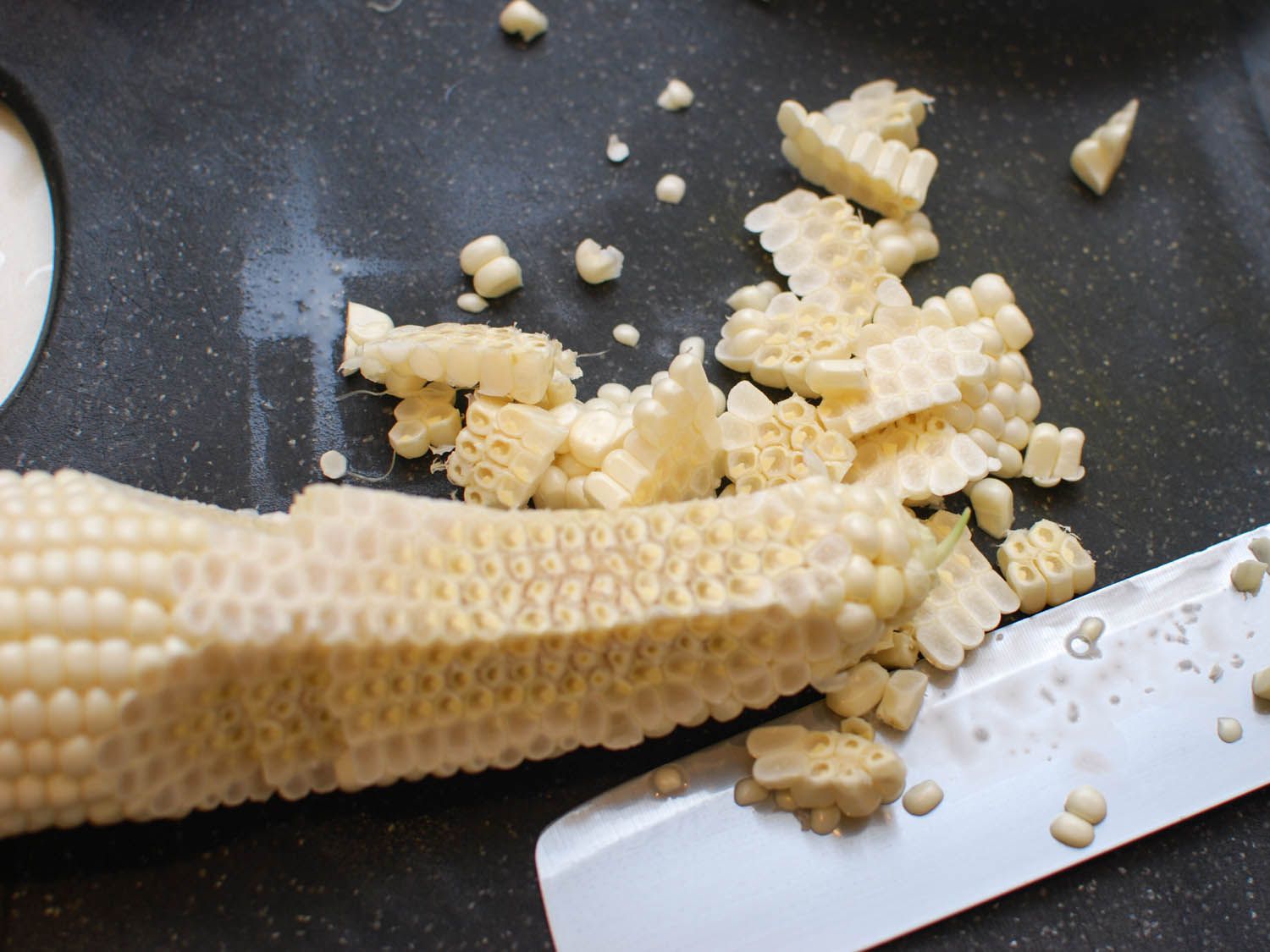 Cutting sweet corn off the cob with a chef's knife.