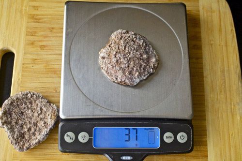 A cooked In-N-Out hamburger patty on a scale showing 37 grams weight.