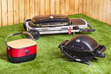 three portable gas grills on a grassy surface