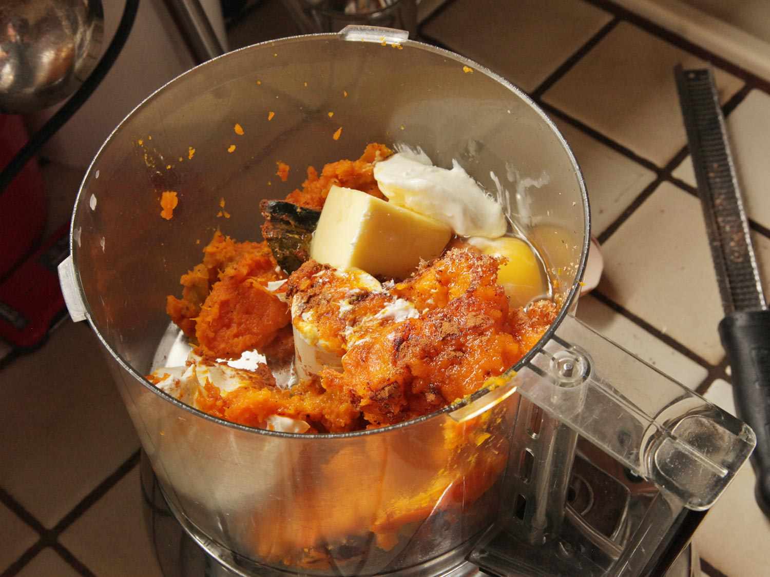 把烤好的南瓜肉、黄油、鸡蛋和香料放在食品加工机的碗里。