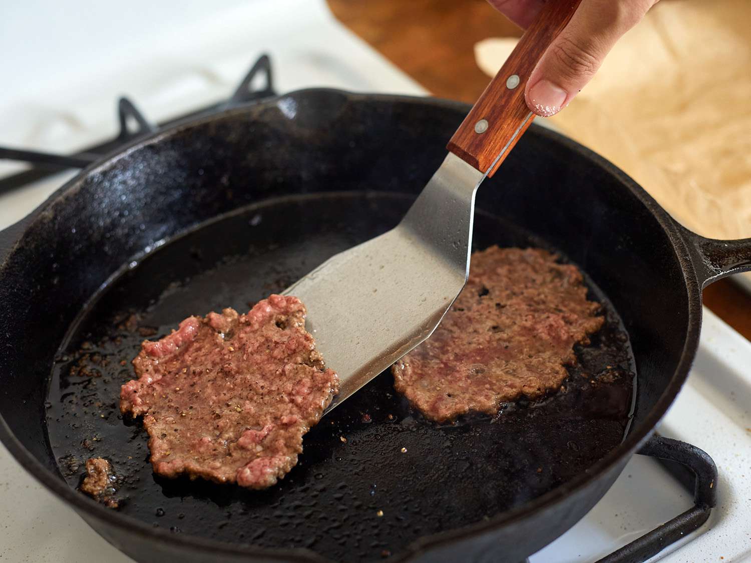 一个偏移金属特纳从一个铸铁煎锅中举起一个粉碎的汉堡。