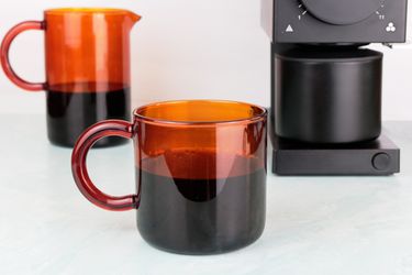 手动琥珀色玻璃咖啡杯旁边玻璃水瓶和咖啡研磨机