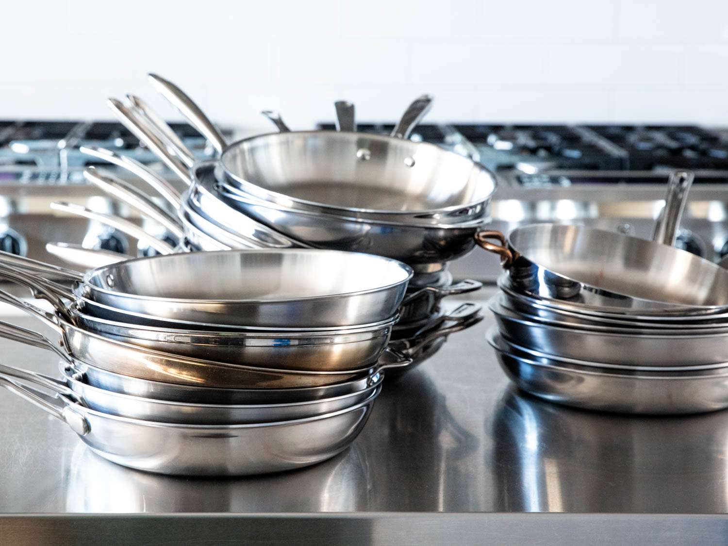 厨房的工作台上摆放着一堆堆不锈钢煎锅。