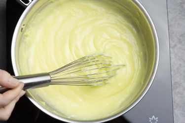 Making pastry cream in a saucier with a hand mid-whisk.