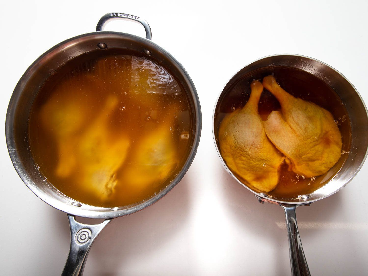 头顶的炖锅里放着传统的和曲腌的鸭腿，上面覆盖着烹饪前融化的鸭油。