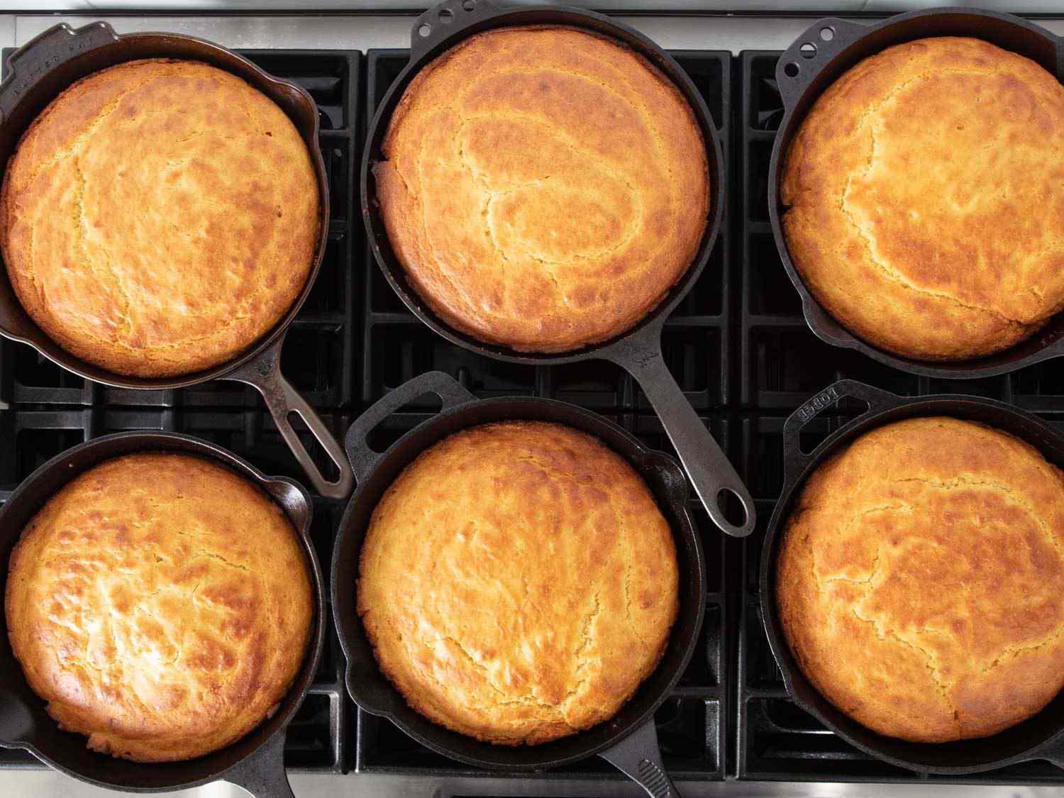 An overhead shot of several cast iron skillets, each containing golden brown cornbread; the differences from skillet to skillet were impossible to discern.