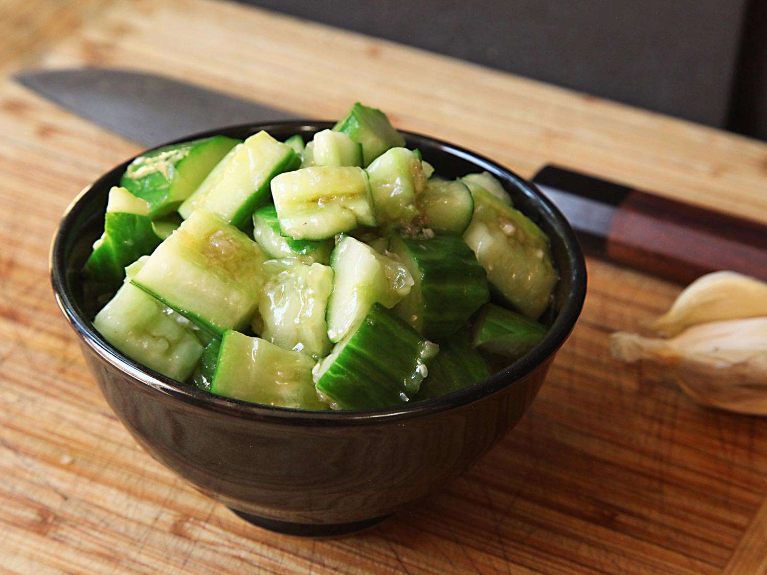 A bowl of crisp and tender cucumbers in a vinegary dressing.