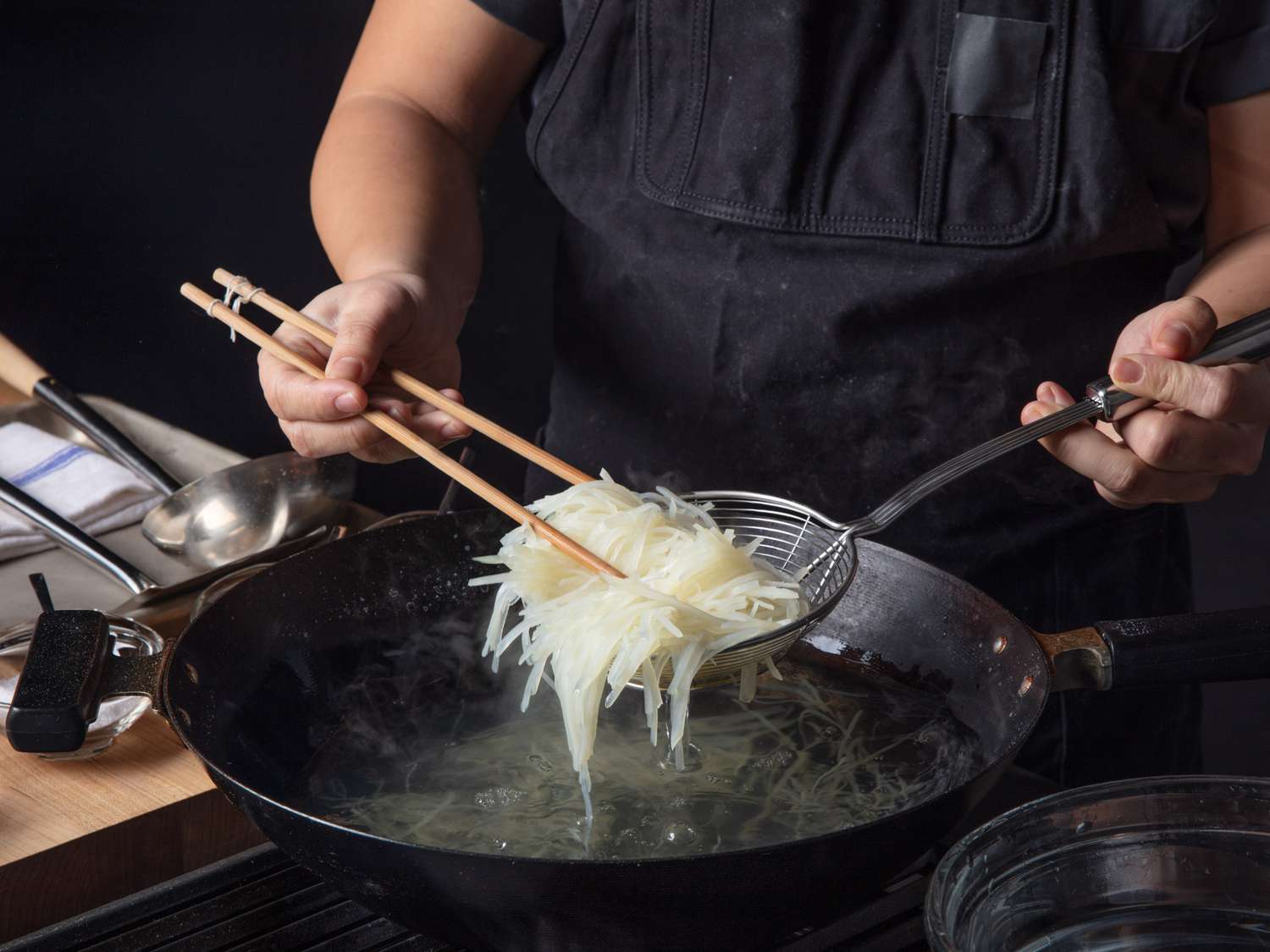 将焯过水的土豆丝从沸水锅中捞出，用筷子夹住