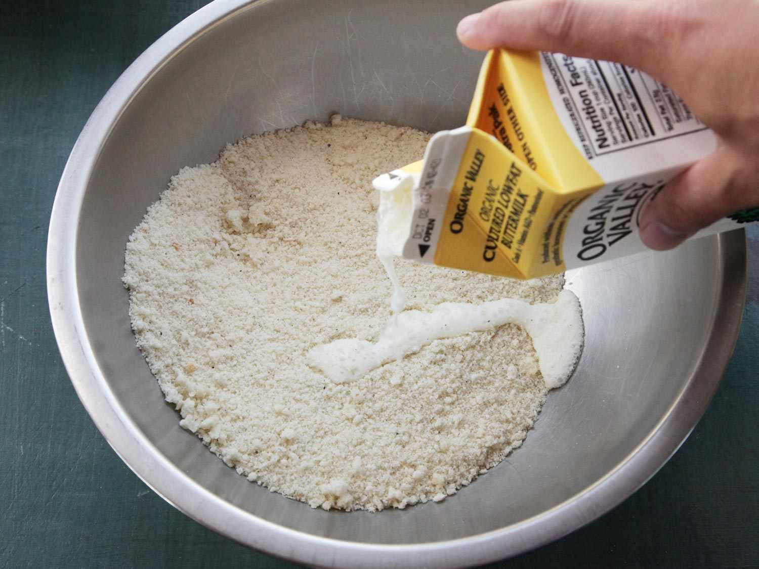 Adding buttermilk into bowl of dry bread crumbs