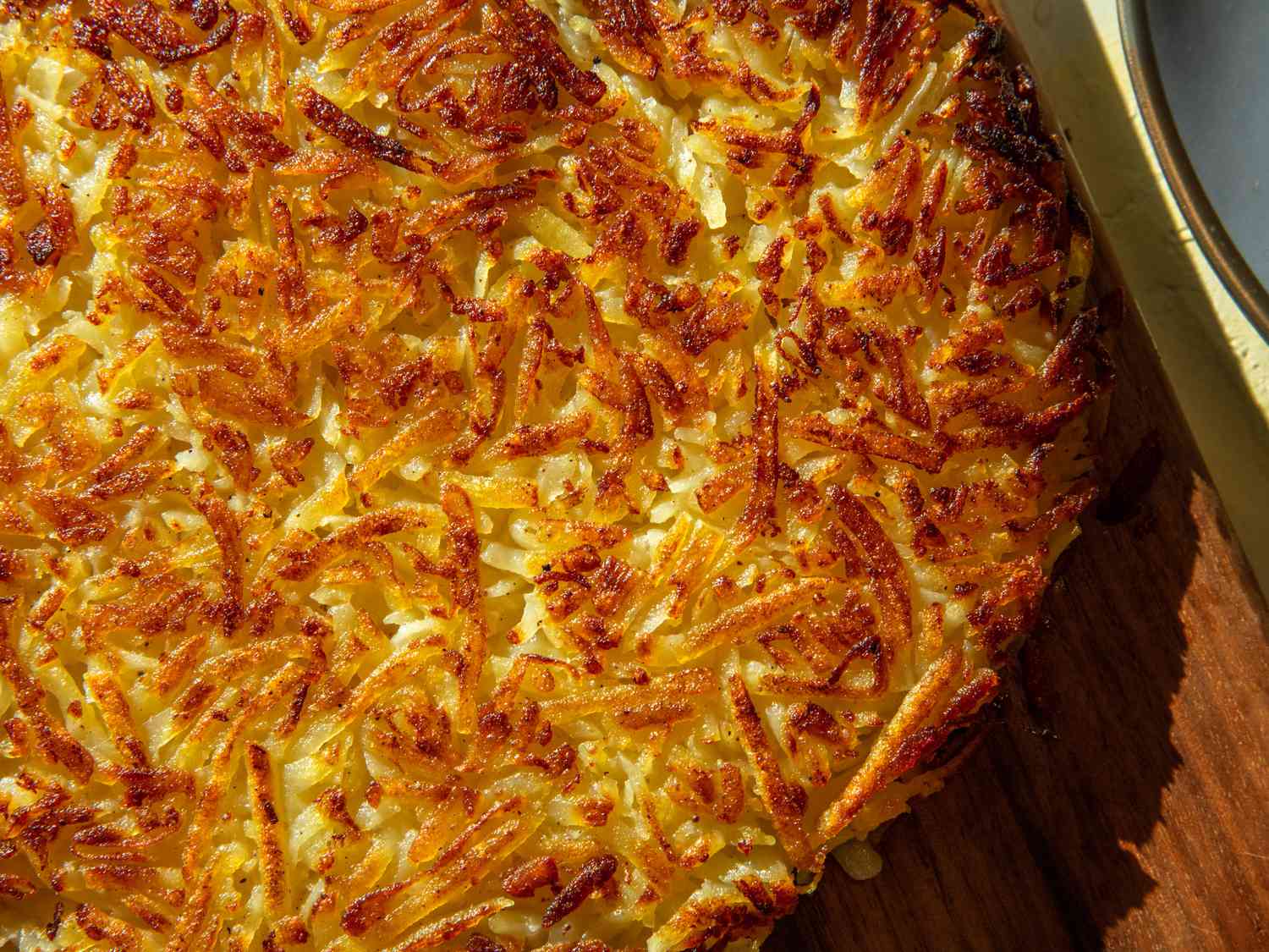 RÃ¶sti, finished on a platter, showing deep browning and crisping on surface.