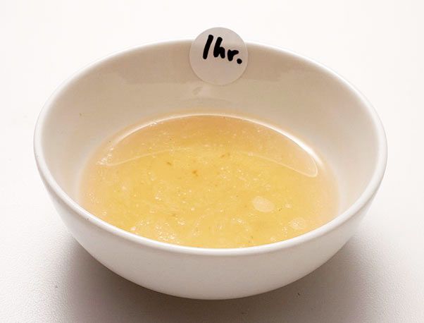 一小碗金黄色的猪肉汤，上面有一张写着一小时的贴纸。
