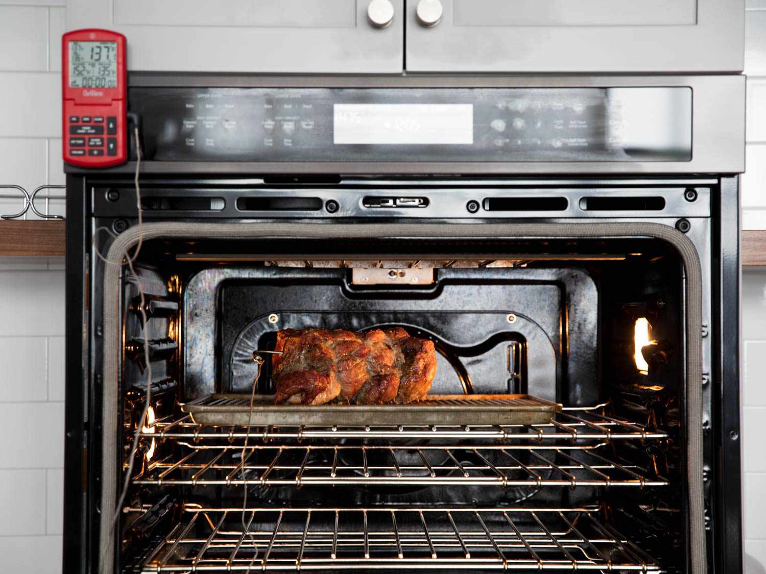 一只鸡在烤箱里烤，烤箱外面有一个探头温度计面板