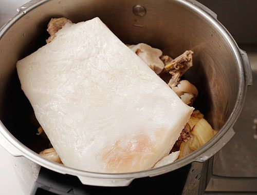 一块肥肉放在汤锅里的一堆骨头上。