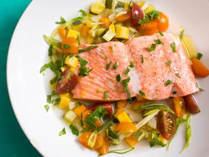把鲑鱼片放在夏季蔬菜和肉汤上，轻轻煮熟