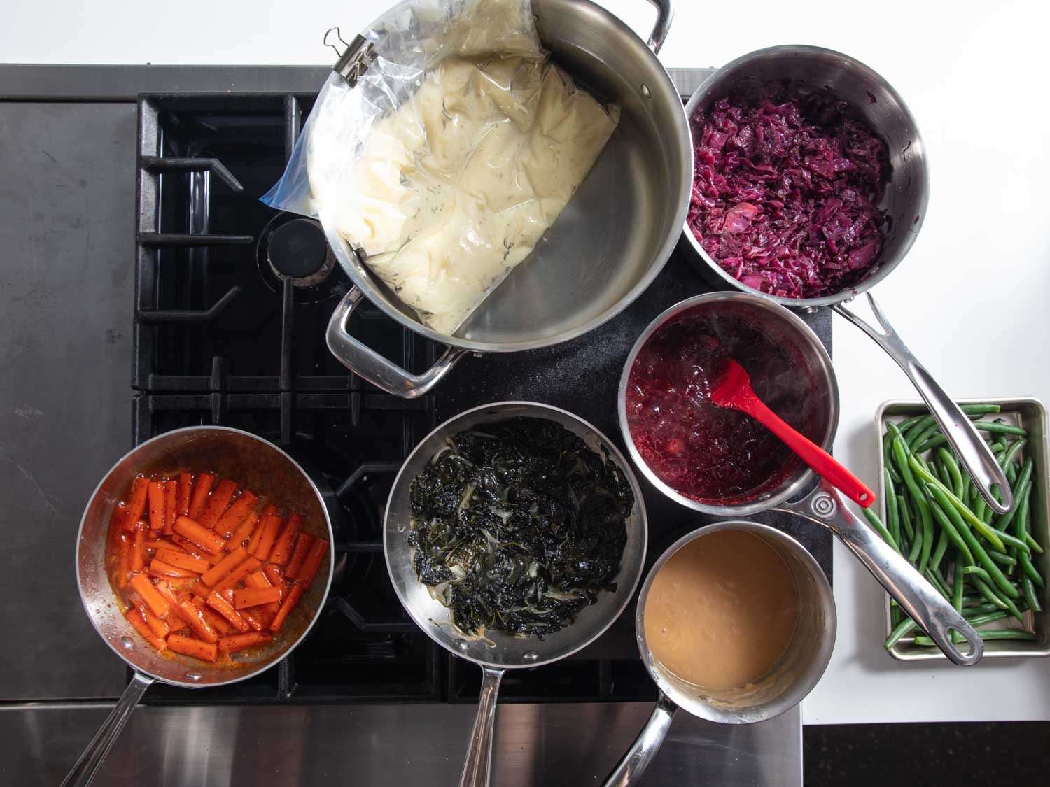 开销的一系列烘焙钢铁设置站变暖锅,平底锅的土豆泥、肉汁、蔓越莓酱,炖甘蓝、红球甘蓝,釉面胡萝卜。