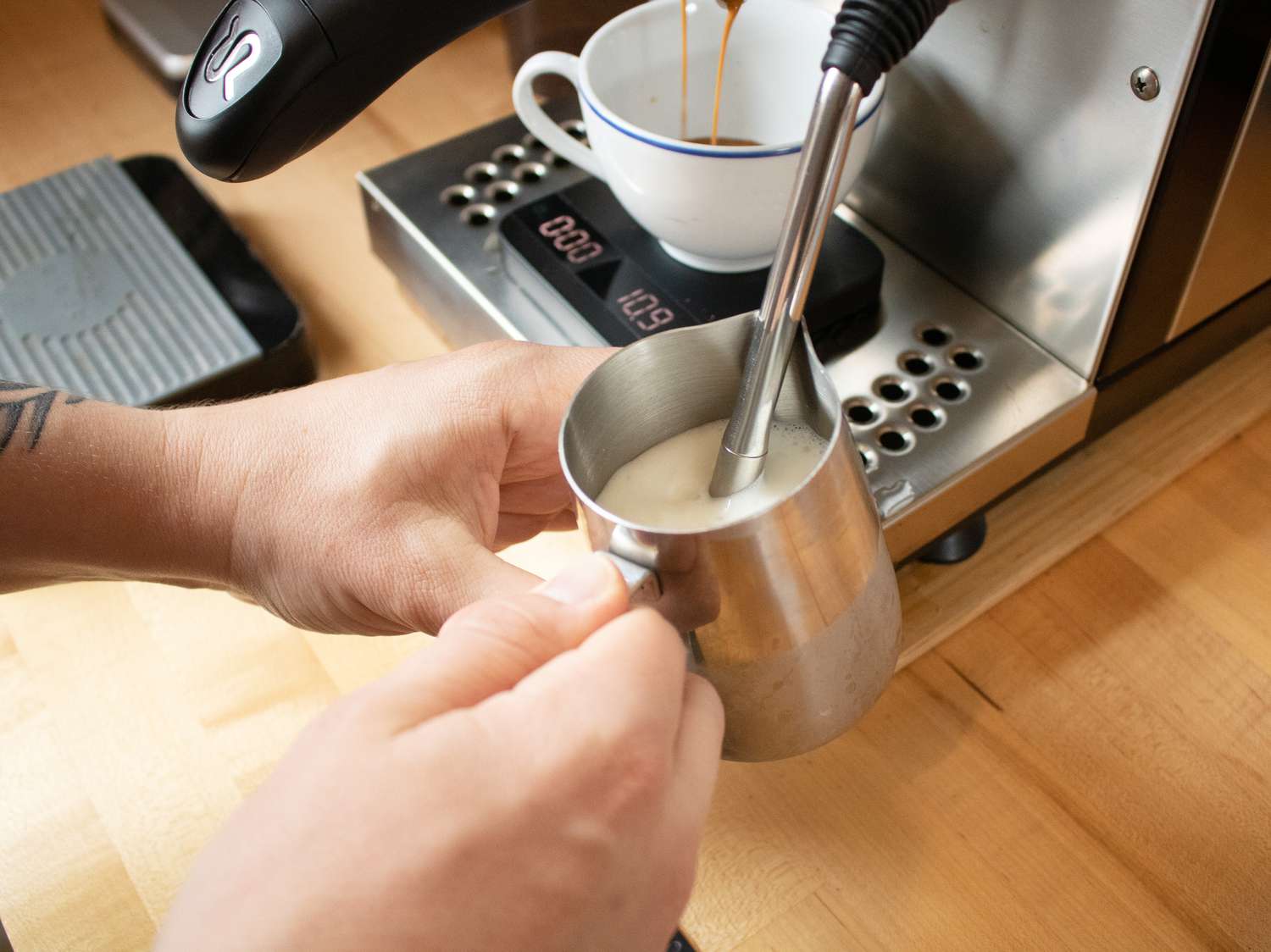 手热气腾腾的牛奶浓缩咖啡机的蒸汽魔杖时拉一个浓咖啡