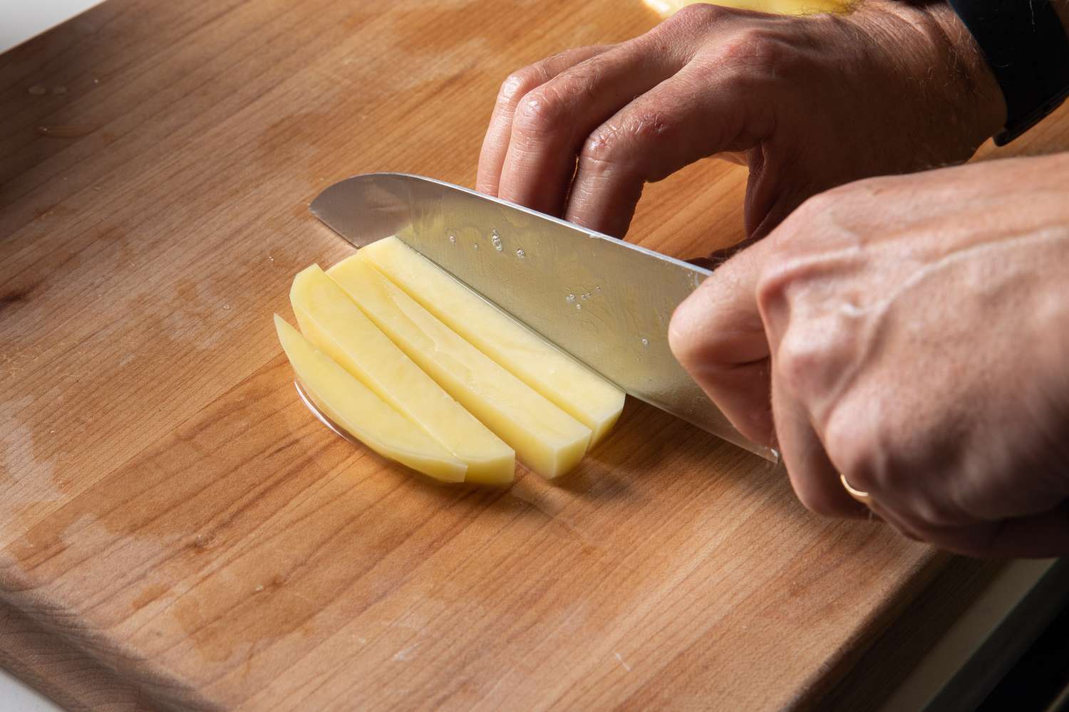 Slicing thick batons of potato by hand for French fries