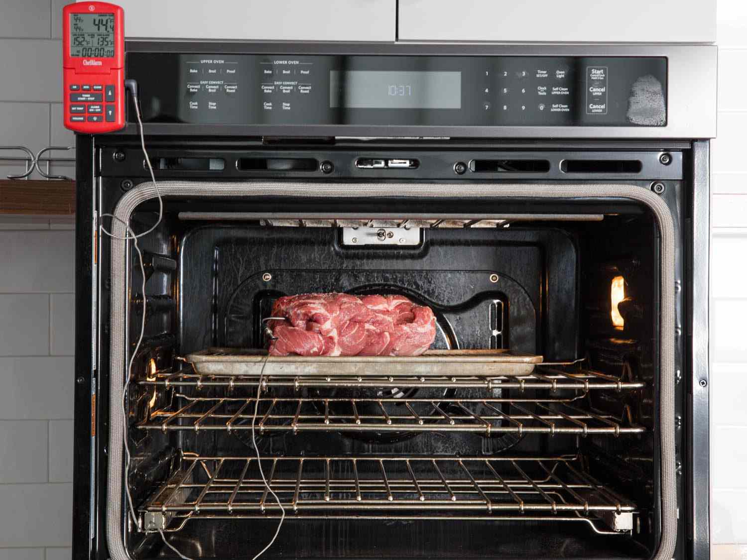 A pork loin roasting in the oven with a probe thermometer attached to it