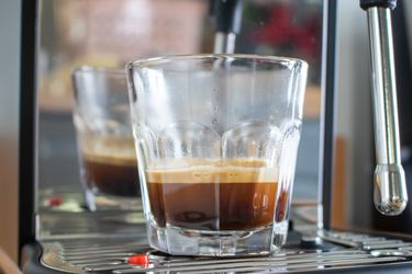 一个透明的玻璃杯，里面装着来自Breville Bambino Plus浓缩咖啡机的双倍浓缩咖啡