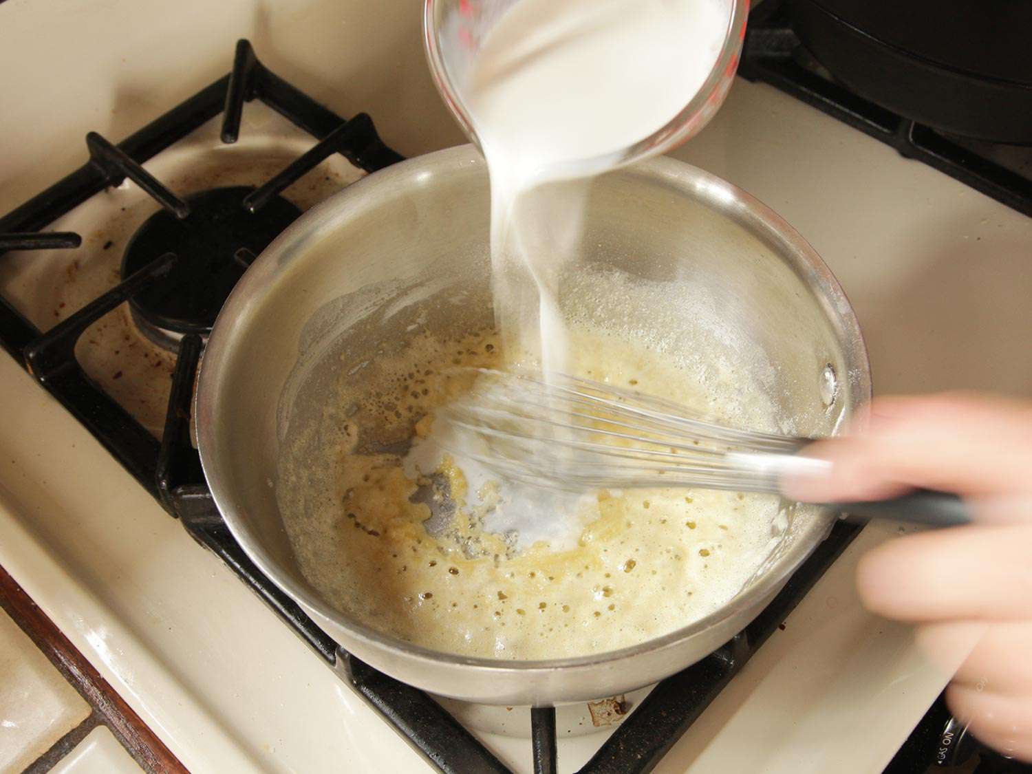 在一锅面粉糊中搅拌牛奶。