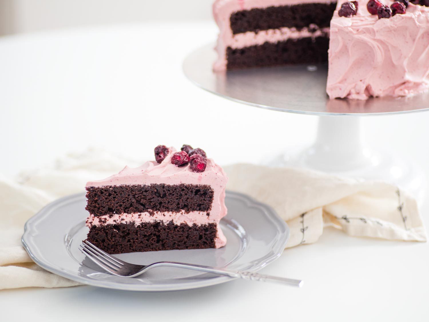 一块两层巧克力蛋糕，涂上淡粉色的樱桃鲜奶油，放在盘子里，剩下的蛋糕放在背景架上
