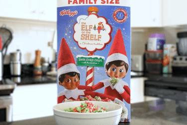 一盒Kellogg's The Elf on The Shelf麦片放在柜台上，前面放着一个碗